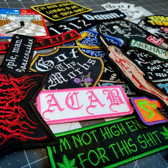 A collection of horror, heavy metal, and board game related embroidered patches from Thread By Dawn.