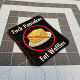 Embroidered patch showing a crossed-out stack of pancakes with the words eff pancakes, eat waffles.