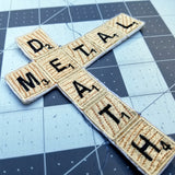 Close up detail of an embroidered patch of the words death metal in Scrabble letters.