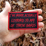 Red on black embroidered patch that says I've never actually listened to any of these bands.