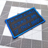 Blue on black embroidered patch that says I've never actually listened to any of these bands.