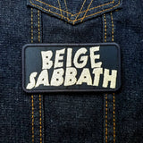 Rectangular tan on black embroidered patch with the words beige sabbath in the logo style of the classic rock band black sabbath. Shown on a denim jacket.
