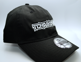Right side view of a black baseball hat with a heavy metal style logo for the classical music composer Tchaikovsky embroidered on the front in white thread.