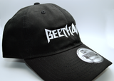 right side view of a black baseball hat with a heavy metal style logo for the classical music composer Beethoven embroidered on the front in white thread.