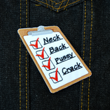 An embroidered patch of a clipboard with red checkmarks next to the words neck, back, pussy, and crack. Shown on a denim jacket.