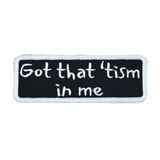 Rectangular black patch with a white border and the words, got that tism in me, embroidered in white thread.