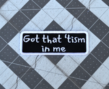 Rectangular black patch with a white border and the words, got that tism in me, embroidered in white thread.