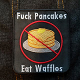 Embroidered patch showing a crossed-out stack of pancakes with the words eff pancakes, eat waffles.