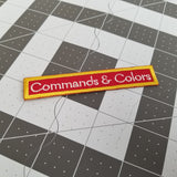 Embroidered text patch for the classic historical wargame Commands and Colors in white and gold on red fabric.