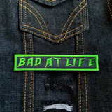 Bad At Life embroidered patch in green on black.