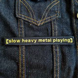 An embroidered patch reading slow heavy metal playing, based on the classic internet meme of a movie subtitle.