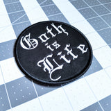 Round black embroidered patch that says goth is life in old english lettering.