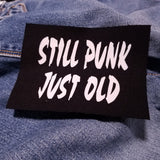 White on black screen printed canvas patch that says still punk, just old.