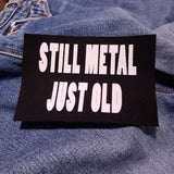 White on black screen printed canvas patch that says still metal, just old.