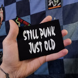 White on black screen printed canvas patch that says still punk, just old. Shown in the palm of a hand for size reference.