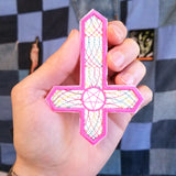 Inverted cross embroidered patch with hot pink and multicolor thread.