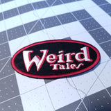 Embroidered patch of the logo for the classic horror and science fiction journal Weird Tales.