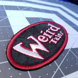 Embroidered patch of the logo for the classic horror and science fiction journal Weird Tales.