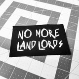 A white on black screen printed canvas patch that says no more landlords in graffiti lettering.