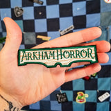 Embroidered patch for the Arkham Horror series of board games and card games. Shown in the palm of a hand for size reference.