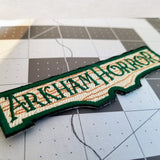 Close up detail of an embroidered patch for the Arkham Horror series of board games and card games.