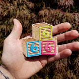 An embroidered patch of baby blocks with the numbers 6,6, and 6 shown in the palm of a hand for size reference.