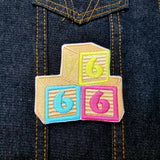 An embroidered patch of baby blocks with the numbers 6,6, and 6.