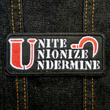 Red, white, and black rectangular patch that says unite, unionize, undermine.