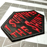 Close-up detail of a red on black embroidered patch that says I survived the shunt, in reference to the horror movie Society.