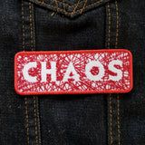 Red on white embroidered patch with hundreds of  random lines of thread spelling the word chaos.