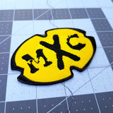 The MXC (Most Extreme Elimination) logo as an embroidered patch.