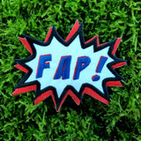 An embroidered patch in the shape of a comic book sound effect bubble with the word fap.