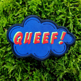 An embroidered patch in the shape of a comic book sound effect bubble with the word queef.