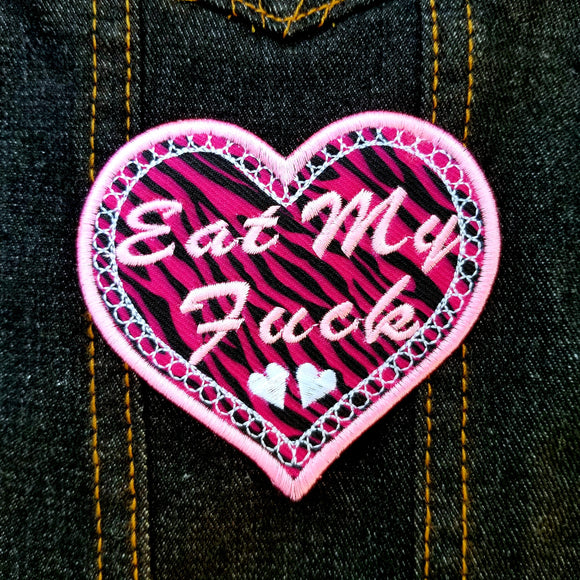 A heart-shaped embroidered Valentines patch with black and pink leopard print, white lace border, and the words eat my fuck.