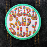 Circular embroidered patch with a bright green border, white background, and the words weird and silly in groovy rainbow lettering.