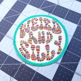 Circular embroidered patch with a bright green border, white background, and the words weird and silly in groovy rainbow lettering.