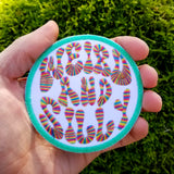 Circular embroidered patch with a bright green border, white background, and the words weird and silly in groovy rainbow lettering. Shown in the palm of a hand for size reference.