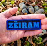 Rectangular two-tone blue on black embroidered logo patch for the cult classic Japanese sci-fi action movie Zeiram. Shown in the palm of a hand for size reference.