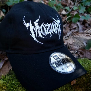 Black baseball cap with a heavy metal style logo for the classical music composer Mozart embroidered on the front in white thread.