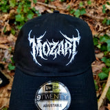 Black baseball cap with a heavy metal style logo for the classical music composer Mozart embroidered on the front in white thread.