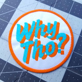 Circular embroidered patch with glittery blue and flat orange lettering saying why though on white fabric.