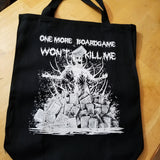 A black canvas tote bag with a white screen printed graphic of a zombie in a pile of boardgames and a caption saying one more boardgame won't kill me.