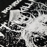 Close up detail of a black canvas tote bag with a white screen printed graphic of a zombie in a pile of boardgames and a caption saying one more boardgame won't kill me.