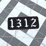 A white on black rectangular embroidered patches with the number 1312.