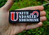 Rectangular black embroidered patch with the words unite, unionize, undermine written in a stencil font, featuring a red sickle. Shown in the palm of a had for size reference.