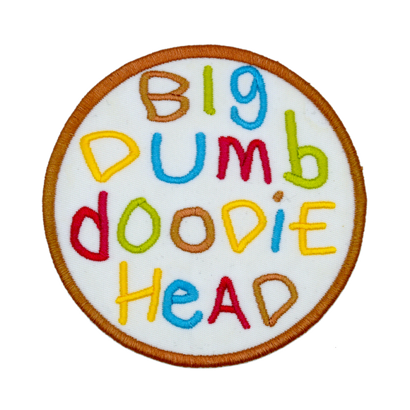 Circular embroidered patch with the words big dumb doodie head in multiple colors written with a childish font.