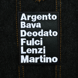 Rectangular white on black embroidered patch with the names of classic Italian film directors, including Argento, Bava, Deodato, Fulci, Lenzi, and Martino. Shown on a denim jacket.