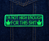 Rectangular green on black embroidered patch that says I'm not high enough for this shit, along with two pot leaves. Shown on a denim vest.