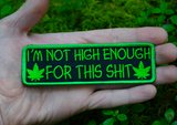 Rectangular green on black embroidered patch that says I'm not high enough for this shit, along with two pot leaves. Shown in the palm of a hand for size reference.