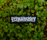 Rectangular white on black embroidered patch with the name of the classical music composer Tchaikovsky stylized to resemble a heavy metal band logo.